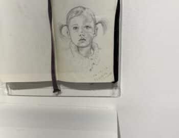 A drawing of a child is displayed on a shelf.