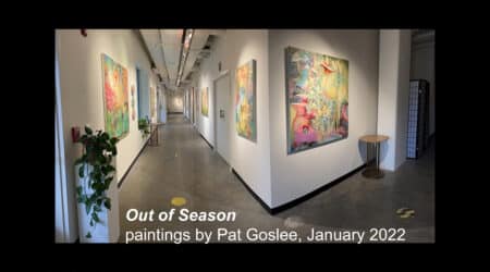 A long corridor in an art gallery featuring colorful paintings by pat goslee, titled "out of season," with a display from january 2022.